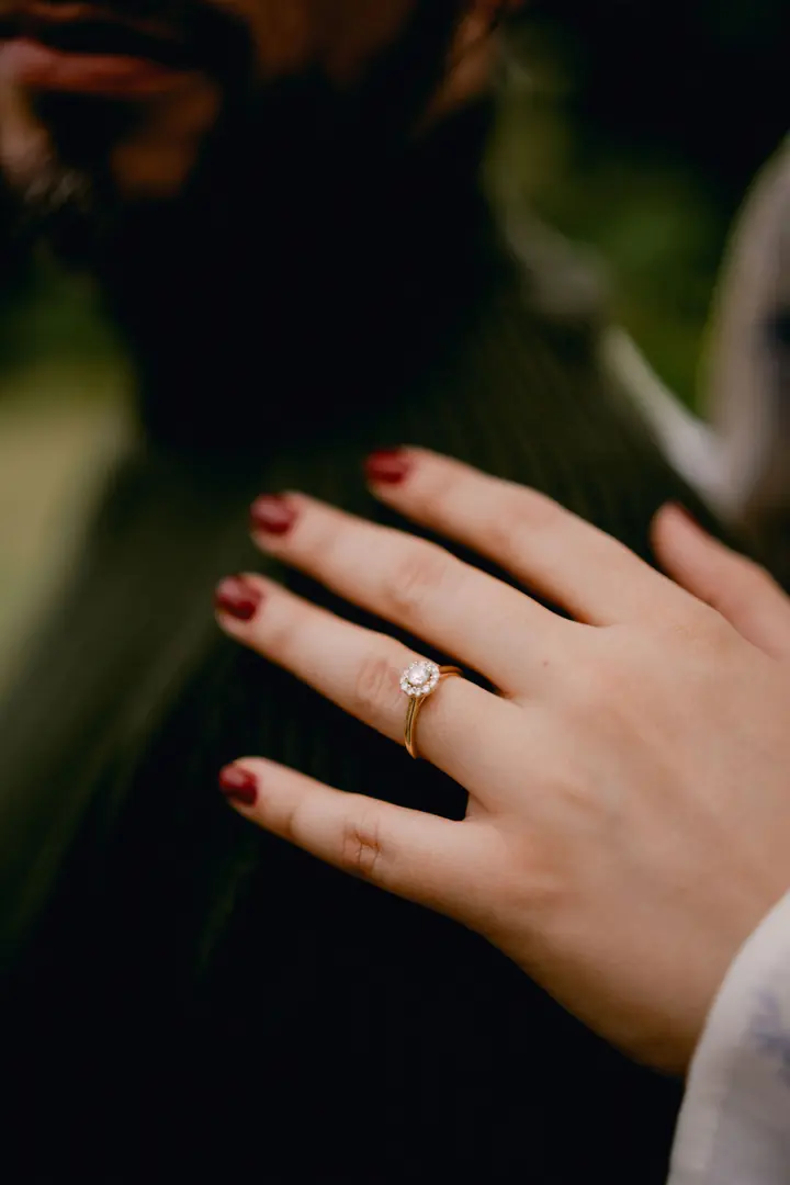La mano de Chanelle con el anillo de compromiso sobre el hombro de Sócrates